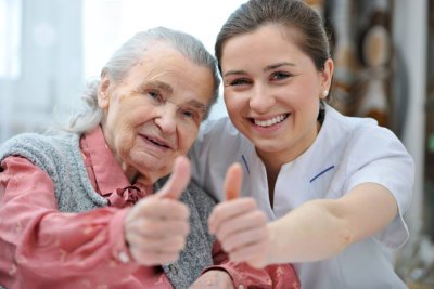 elderly and caregiver giving a thumbs up